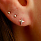 Close-up of an ear with star-shaped earrings and small studs.
