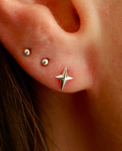 Close-up of an ear with star-shaped earrings and small studs.