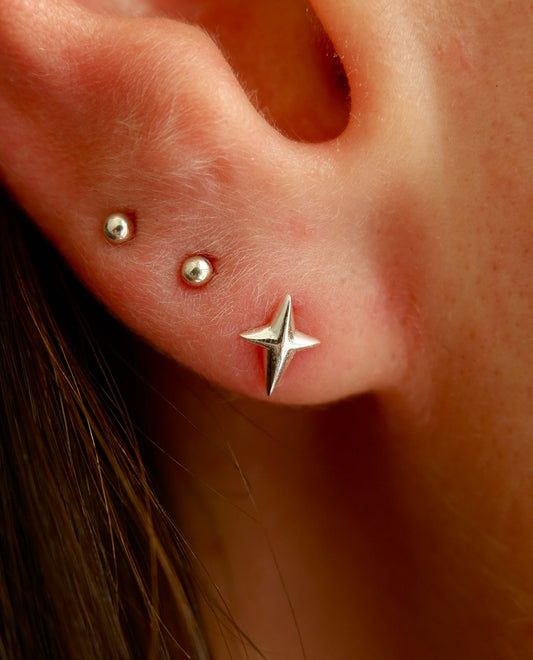 Close-up of an ear with star-shaped earrings and small studs.