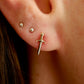Close-up of an ear with a gold sword-shaped earring.